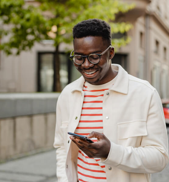 Man holding smart phone while walking down a city sidewalk