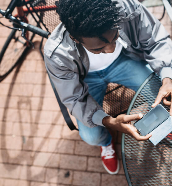 Man taking a picture of a check at a park to deposit his funds