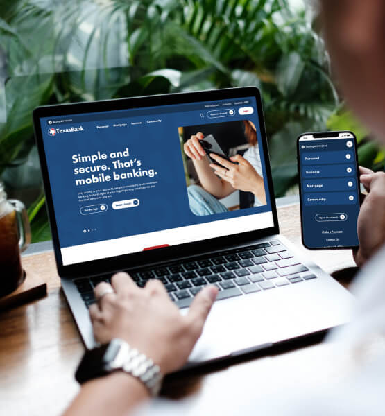 Person sitting a table viewing TexasBank's new website on their laptop and smart phone