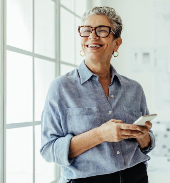 Business woman smiling while holding her smart phone