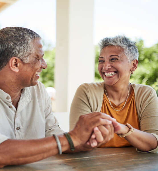 Mature couple holding hands on their porch and smiling