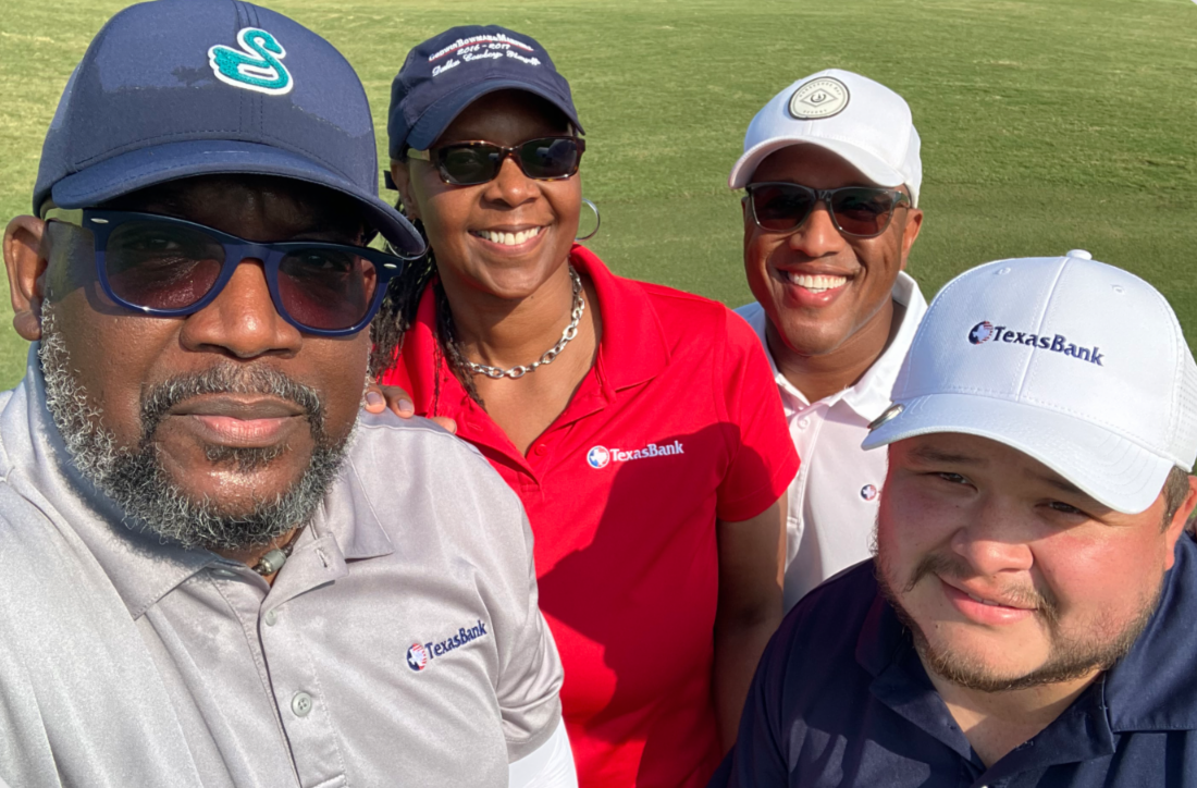 TexasBank employees smiling together outdoors in branded shirts and hats at a community golf event.