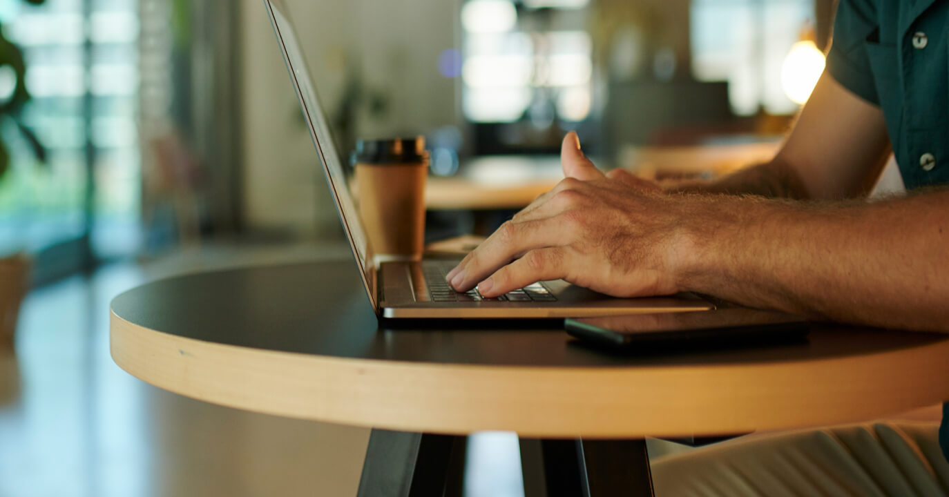 A man typing on a laptop in a coffee shop